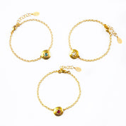 Three gold engraved disc bracelets with blue topaz, moonstone and ruby quartz rest against a white background. December birthstone jewelry, June birthstone jewelry, July birthstone jewelry.