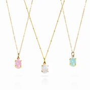 Three vertical prong-set oval cabochon birthstone pendants in yellow gold, rose gold, and bright sterling silver colors, displayed on matching gold-filled chains.