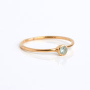 Single rose gold plated dainty 3mm blue topaz gemstone ring. December birthstone, on white background.