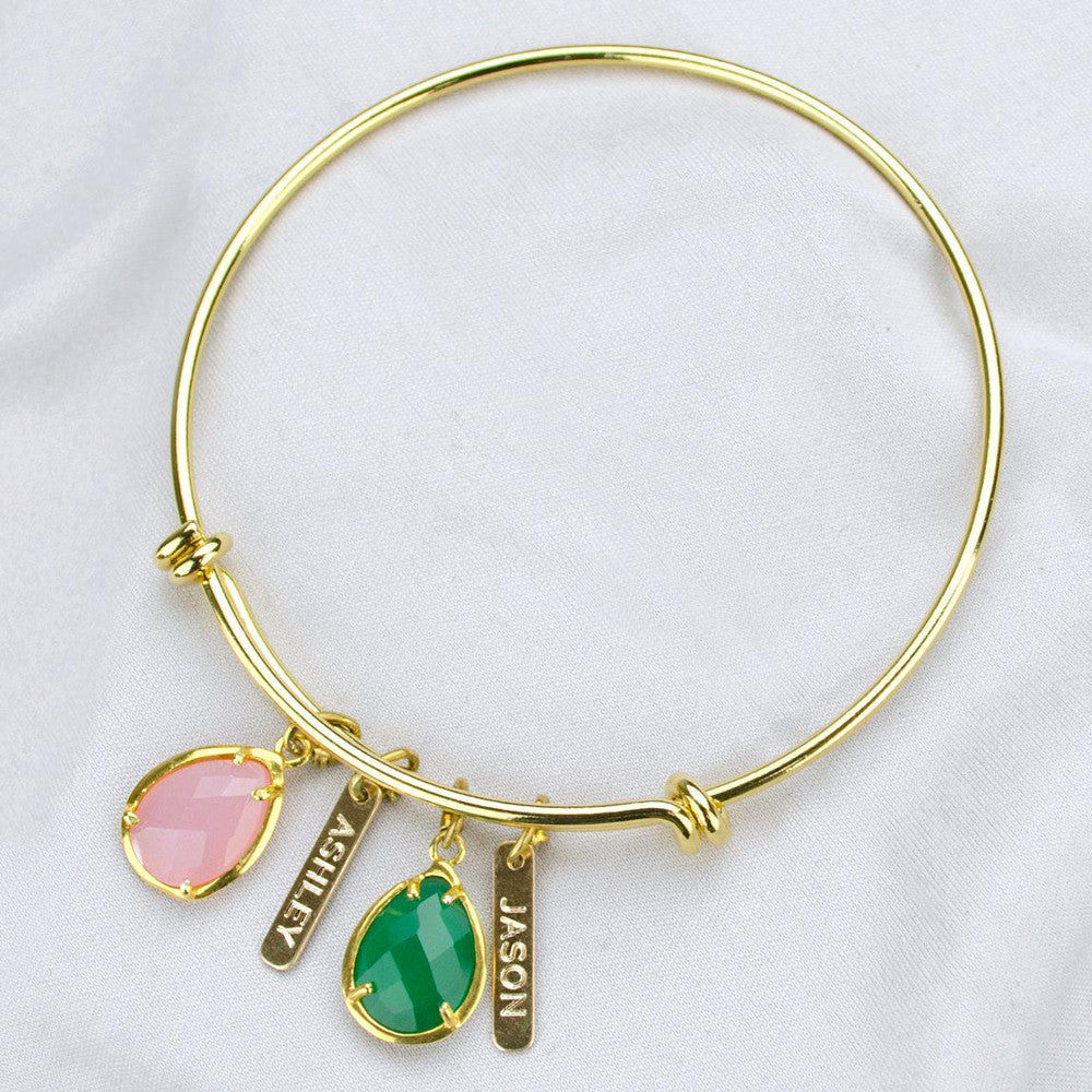 Gold bangle with two engraved name bars and pink chalcedony and green onyx birthstones.