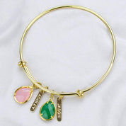 Gold bangle with two engraved name bars and pink chalcedony and green onyx birthstones.