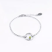 Sterling silver open circle pendant charm birthstone bracelet featuring peridot birthstone. August birthstone, gemstone jewelry on white background.