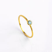 Single gold plated blue topaz dainty 3mm gemstone ring. December birthstone ring on white background.