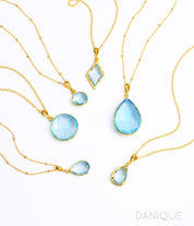 Shop our blue topaz necklace collection available in large, medium and small teardrops, prong set teardrop, prong set diamond, large and medium rounds on white background. Choose from satellite or cable chain. December birthstone.