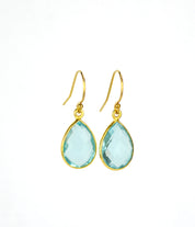 Small gold filled teardrop blue topaz birthstone earrings on a white background. Blue topaz gemstone, december birthstone.