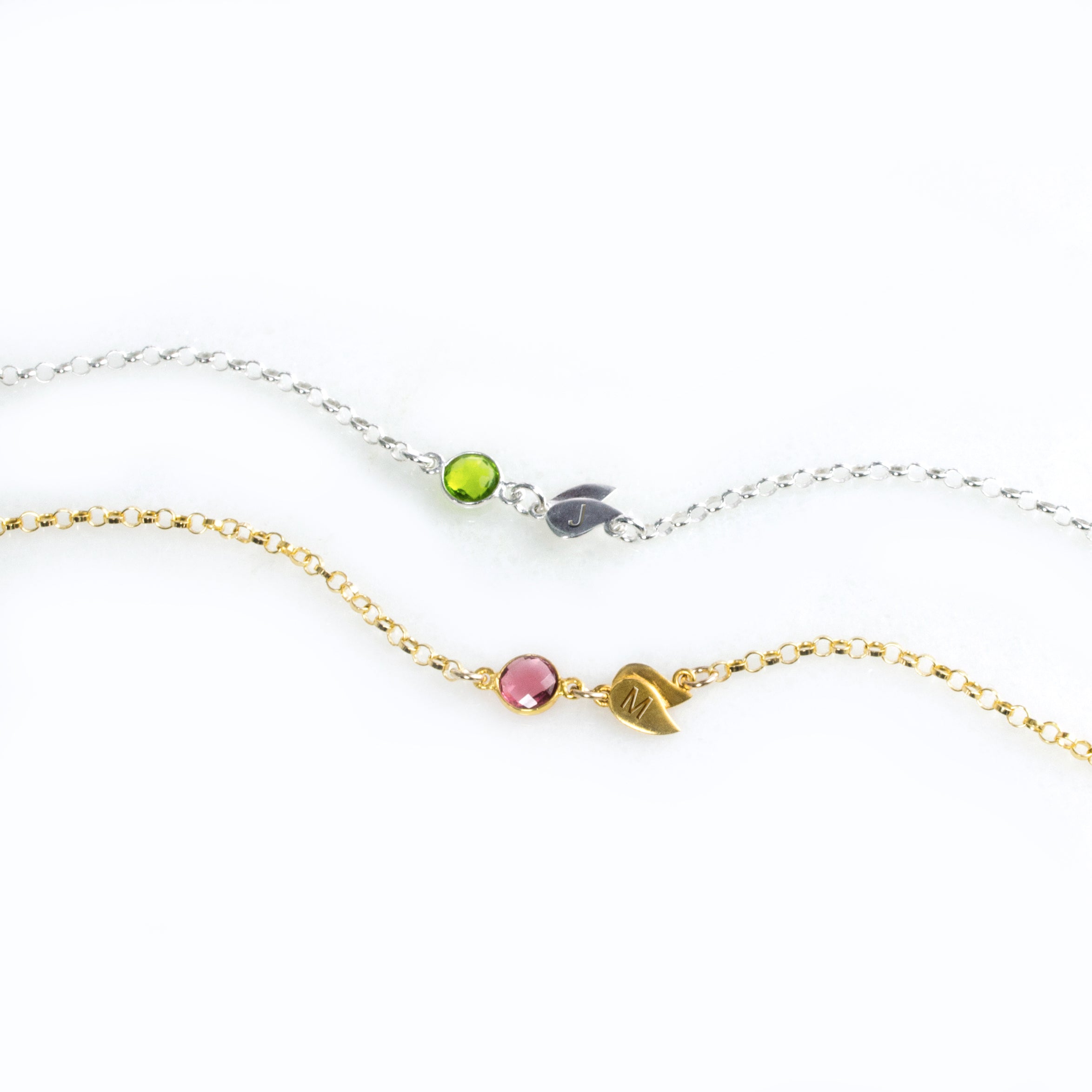 Single sterling silver double leaf initial charm with peridot birthstone. August birthstone, august gemstone, august birthday Gold filled double leaf charm with initial engraved and ruby birthstone on a white background. Ruby gemstone charm name