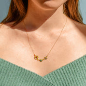 Model in green top is wearing the bloom mom of two necklace with garnet, peridot and purple amethyst birthstones in gold filled.