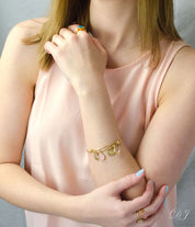 Model in beige top is wearing the name bangle bracelet with pink chalcedony and clear quartz birthstones.