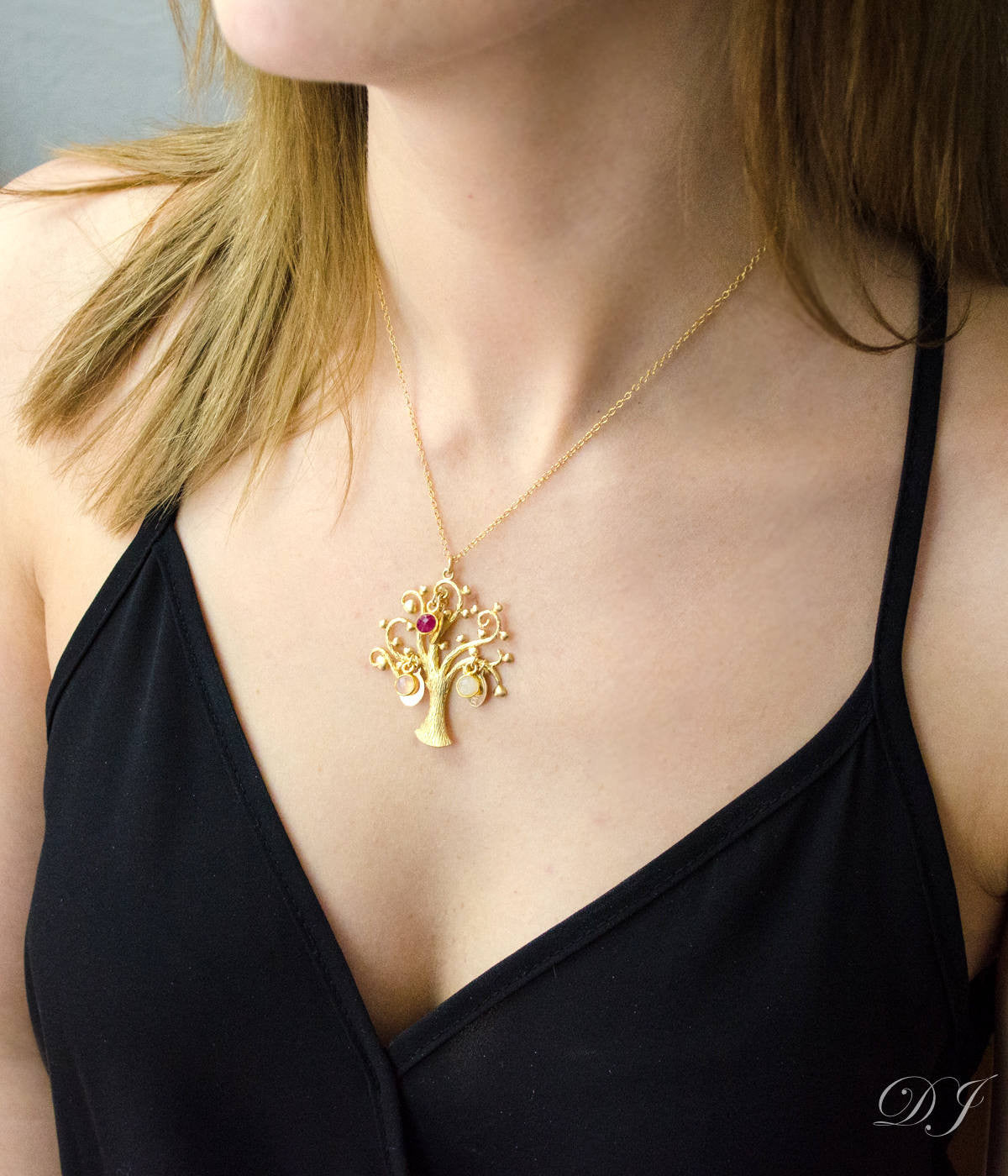 Model in black top wearing gold filled swirly tree necklace with engraved oval name tags and pink chalcedony dyed ruby and opalite birthstones.