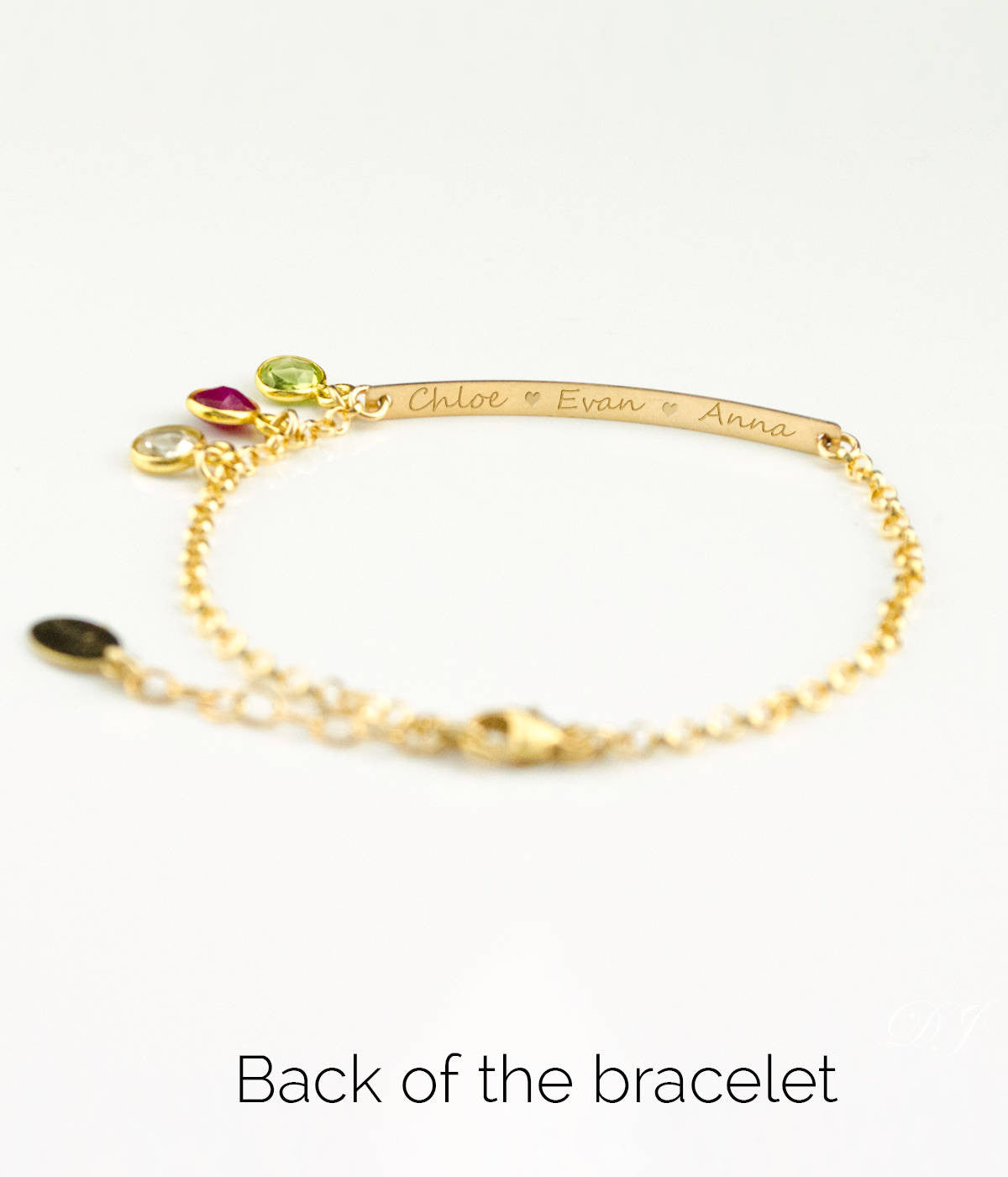 Back of gold filled bracelet has been engraved with names in script font. Peridot, ruby and clear birthstones are shown.