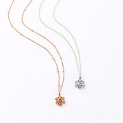Rose gold filled satellite chain with mothers bloom flower pendant and kyanite birthstone. Sterling silver cable chain mothers bloom pendant necklace with blue quartz birthstone on white background.