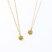 Large gold filled floral flower bloom necklaces. Left features a satellite chain with purple amethyst birthstone. The right necklace is on a cable chain with peridot birthstone.