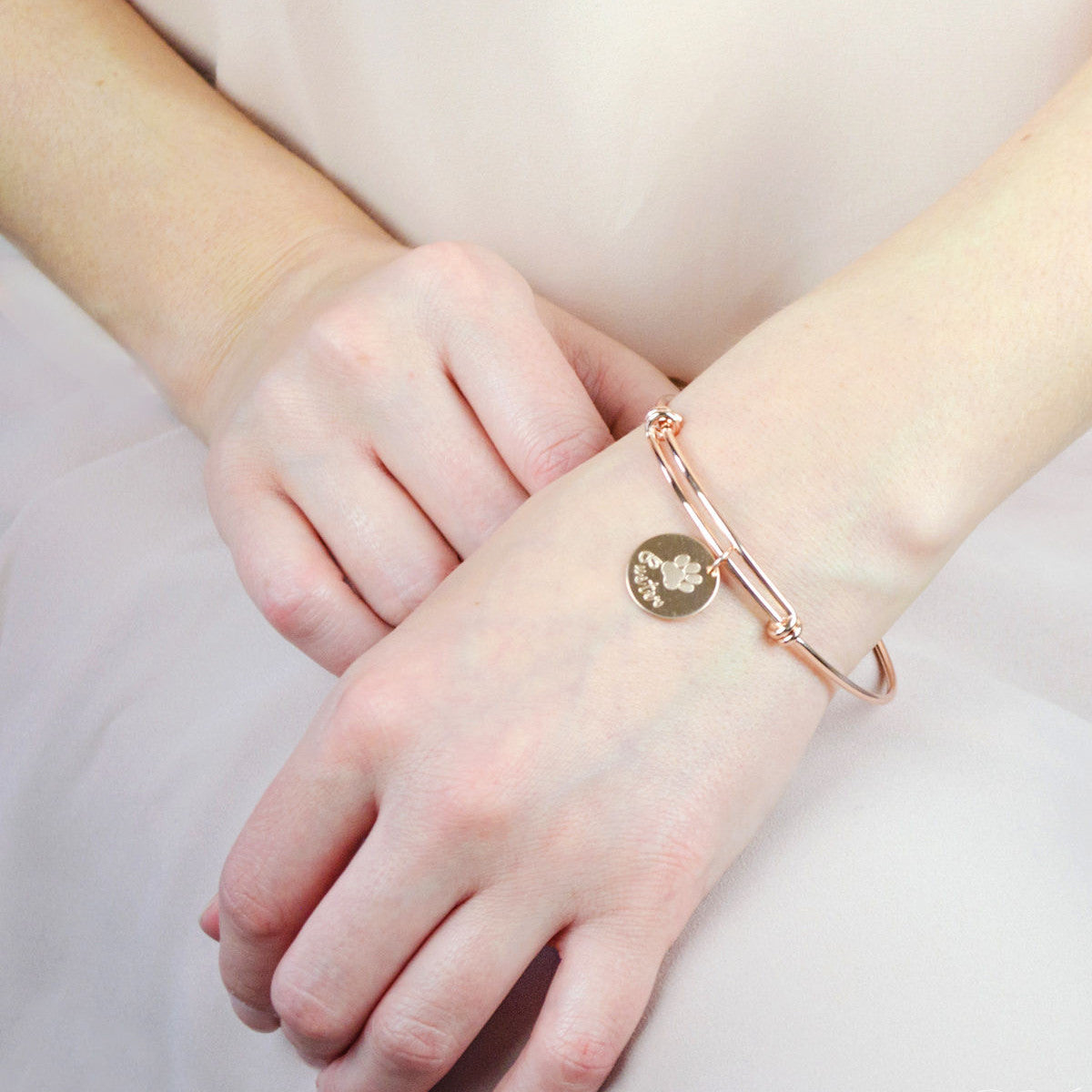 Model wearing stylish rose gold plated paw print disc bangle. Perfect memorial keepsake for any dog mom cat mom.
