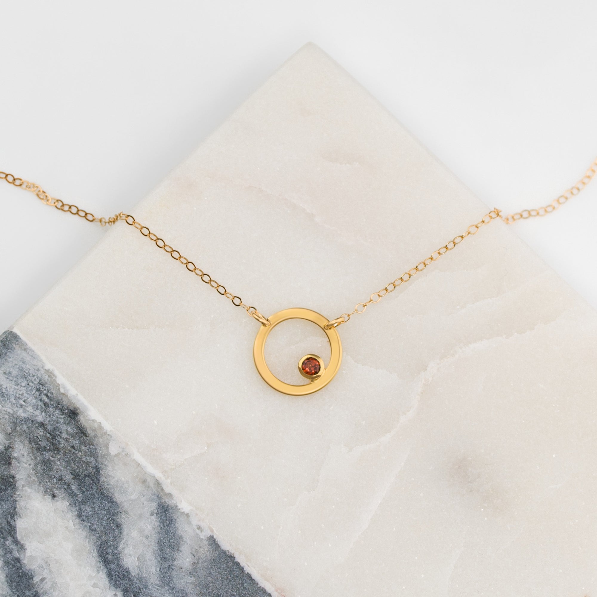 Mother holding young child while wearing a minimalist birthstone circle necklace in sterling silver, a sentimental custom pendant for moms, styled in soft neutral tones for an elegant family portrait.