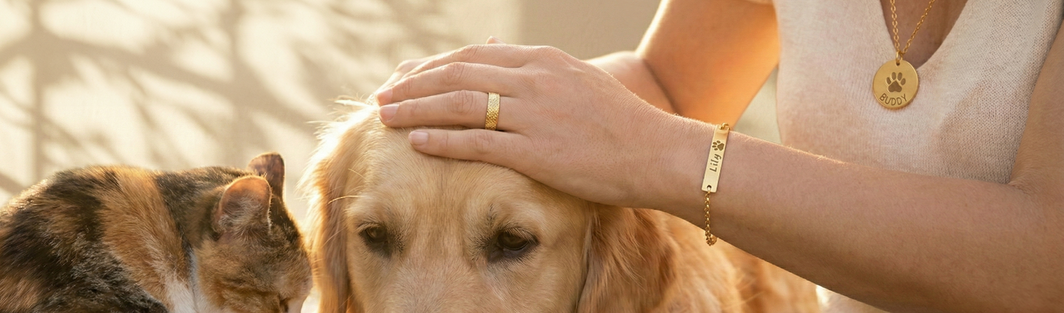 A woman standig next to her dog petting him. A cat is on the far left. The woman wears an assortment of custom engraved pet keepsakes.