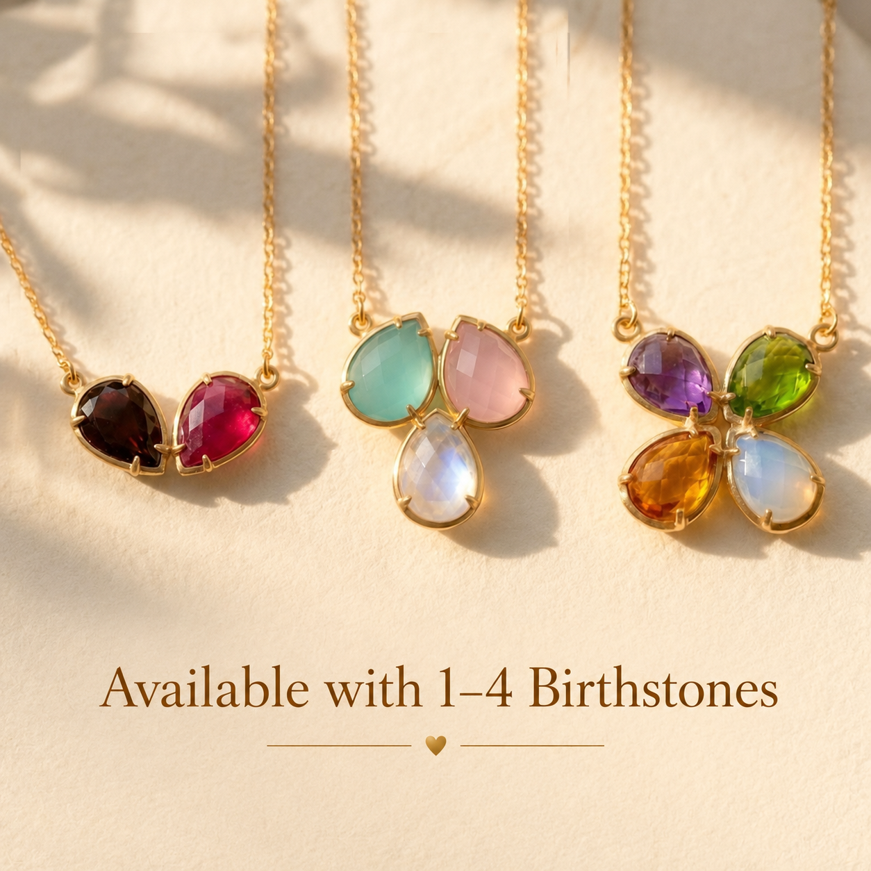 Custom birthstone necklaces shown with one to four colorful teardrop gemstones in yellow gold, representing family members or loved ones.