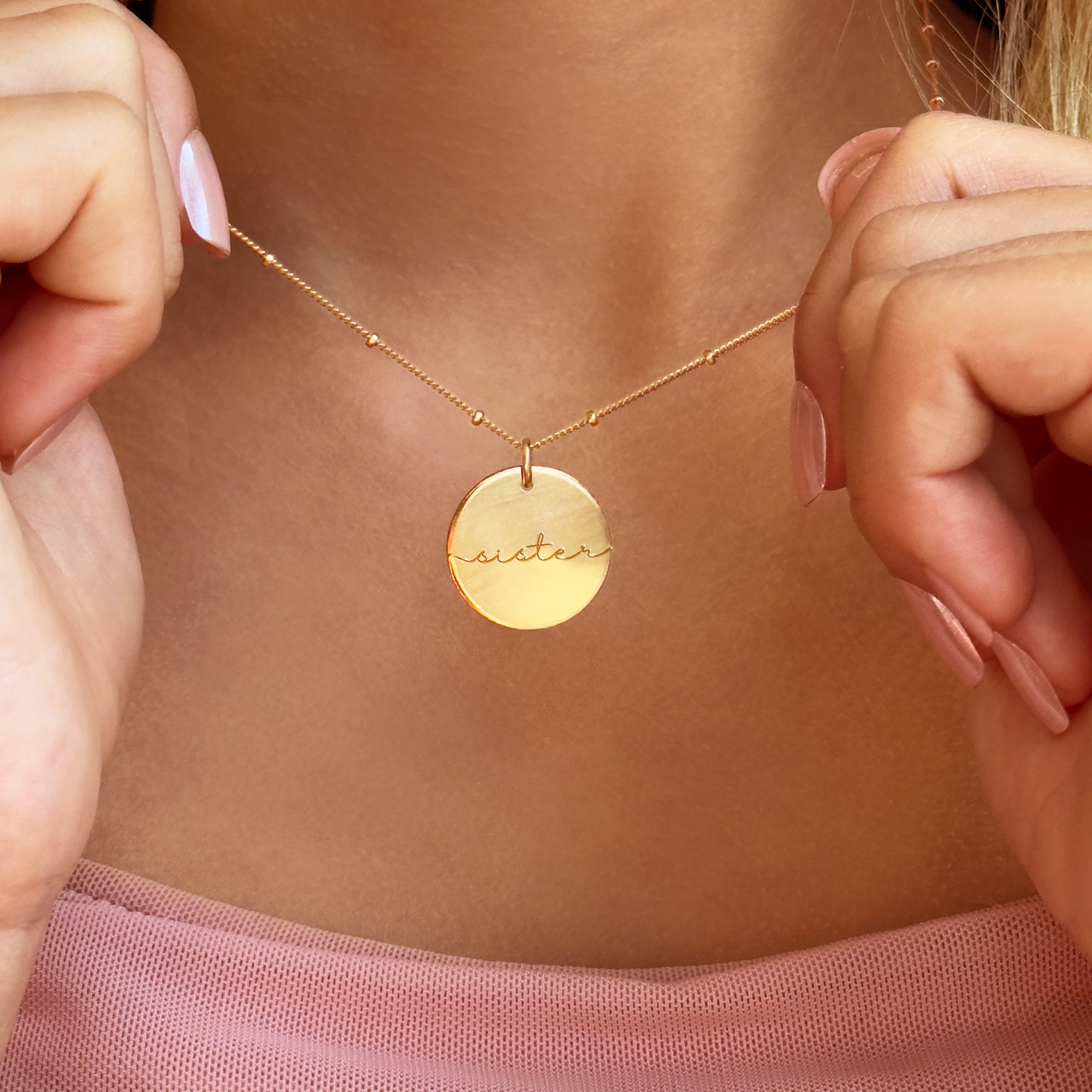 Woman wearing personalized gold name disc necklace, dainty engraved pendant for everyday minimalist style.