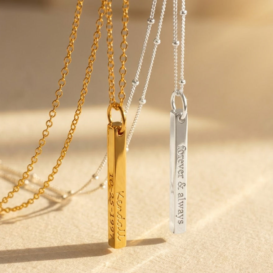 A sleek minimalist engraved 3D bar necklace shown in gold and silver with slim vertical bars engraved “Kendall” and “forever & always,” highlighting deep laser engraving and polished edges. This custom name necklace can feature names, initials, dates or coordinates on up to four sides; available in gold-filled, sterling silver and rose finishes—an elegant everyday keepsake and gift for women or men who love vertical name necklace styles.