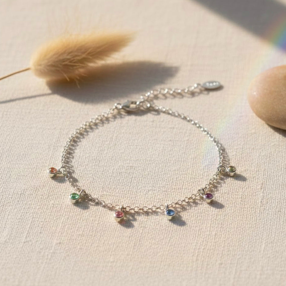 Flat lay of custom birthstone dangle bracelets in gold and silver, minimalist gemstone bracelet designed for moms, grandmas, or bridesmaids, elegant everyday personalized jewelry