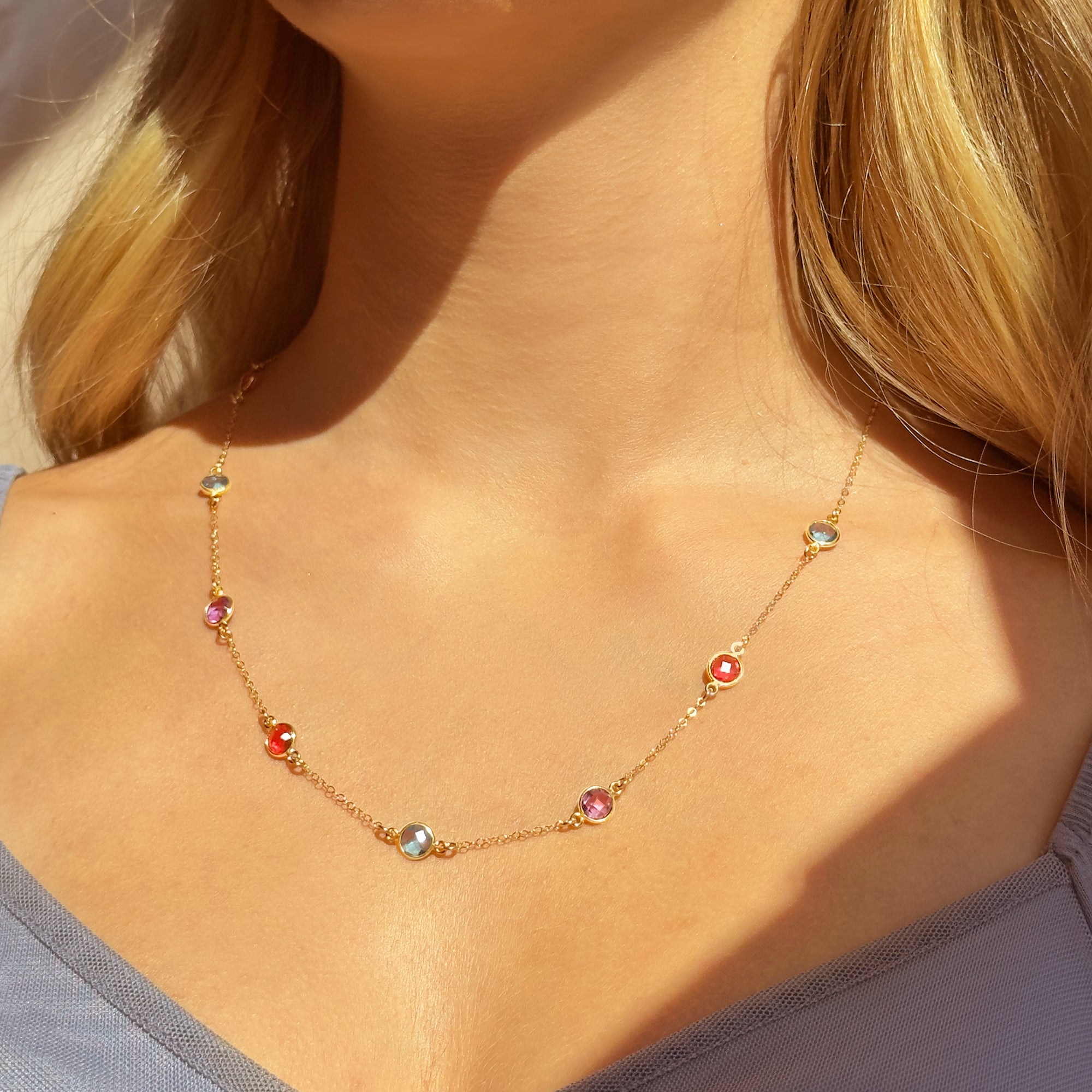 Model wearing Taylor Swift–inspired warm-tone custom birthstone necklace with stations featuring July Ruby, September Sapphire, January Garnet, and October Opal along a gold chain. A meaningful everyday necklace that can be personalized with children's or loved ones’ birth months, perfect for Swifties, moms, grandmas, or friends celebrating birthdays, Mother’s Day, or special milestones with sentimental gemstone jewelry.