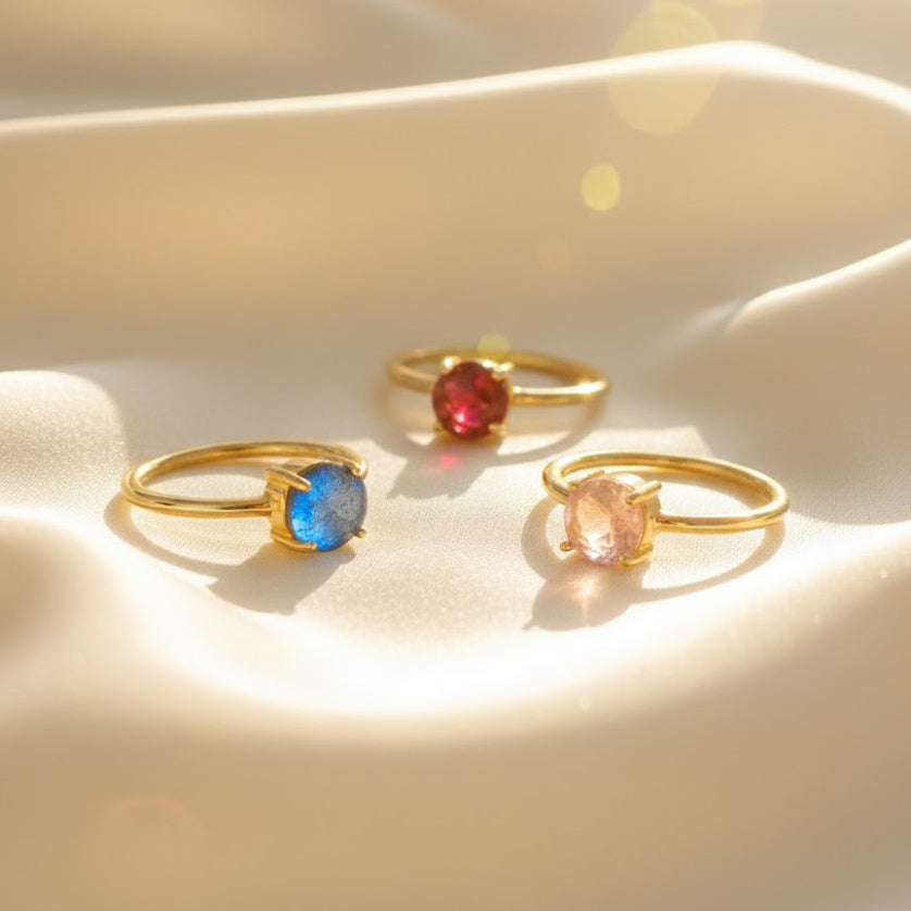 stackable birthstone ring set displayed on champagne satin, featuring ultra-slim gold vermeil and sterling silver bands each with a small faceted gemstone in ruby, citrine, amethyst and peridot, representing loved ones, customizable stacking birthstone rings for mom, grandmother or bridesmaids, minimalist personalized jewelry that grows with family, meaningful gift idea for birthdays, anniversaries, Mother’s Day