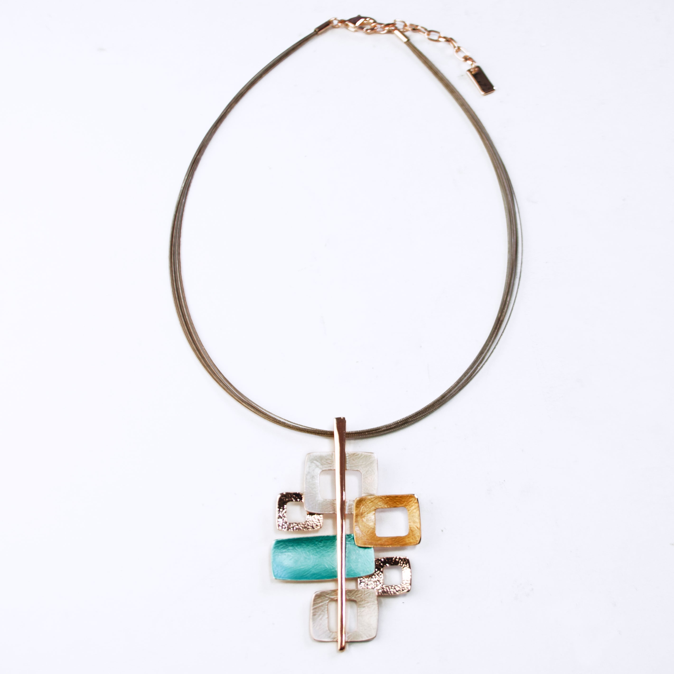 Adjustable Necklace with a brown steel cable chain and a pendant with 6 interlocking squares plated in rose gold and painted in beige, gold, and teal enamel against a white background. Five squares contain square cut outs