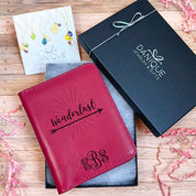 A Raspberry passport holder with the word Wanderlust resting over an arrow and a Swirly Monogram with initials EBS sits in an open Danique Jewelry box. Ready for Gifting Passport Holder with Custom Design and Natural Organic Leather Material in Danique Jewelry gift box. Gift ready.