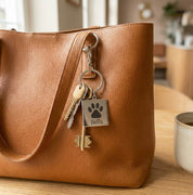 Custom paw print keychain attached to a leather bag, showcasing everyday use and stylish durability. This personalized pet keychain engraved with your dog’s name blends sentiment with function, making it a meaningful dog memorial gift or daily keepsake. Designed for pet lovers who want a subtle, elegant way to carry their dog’s memory everywhere.