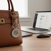 Custom pet portrait keychain attached to handbag near workspace, showcasing everyday use. Personalized engraved pet keychain featuring a detailed animal portrait and name. Durable stainless steel keychain designed for daily carry, making it a thoughtful pet lover gift, memorial keepsake, or meaningful accessory for dog and cat owners.