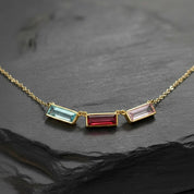 mom birthstone name necklace featuring three slim vertical bar gemstones bezel set in gold and arranged side by side on a delicate chain, icy blue, deep ruby red and soft blush pink birthstones representing children or family members, modern minimalist bar design perfect for personalized mom jewelry, custom birthstone and name combinations available, meaningful Mother’s Day, birthday or Christmas gift that layers beautifully with other necklaces