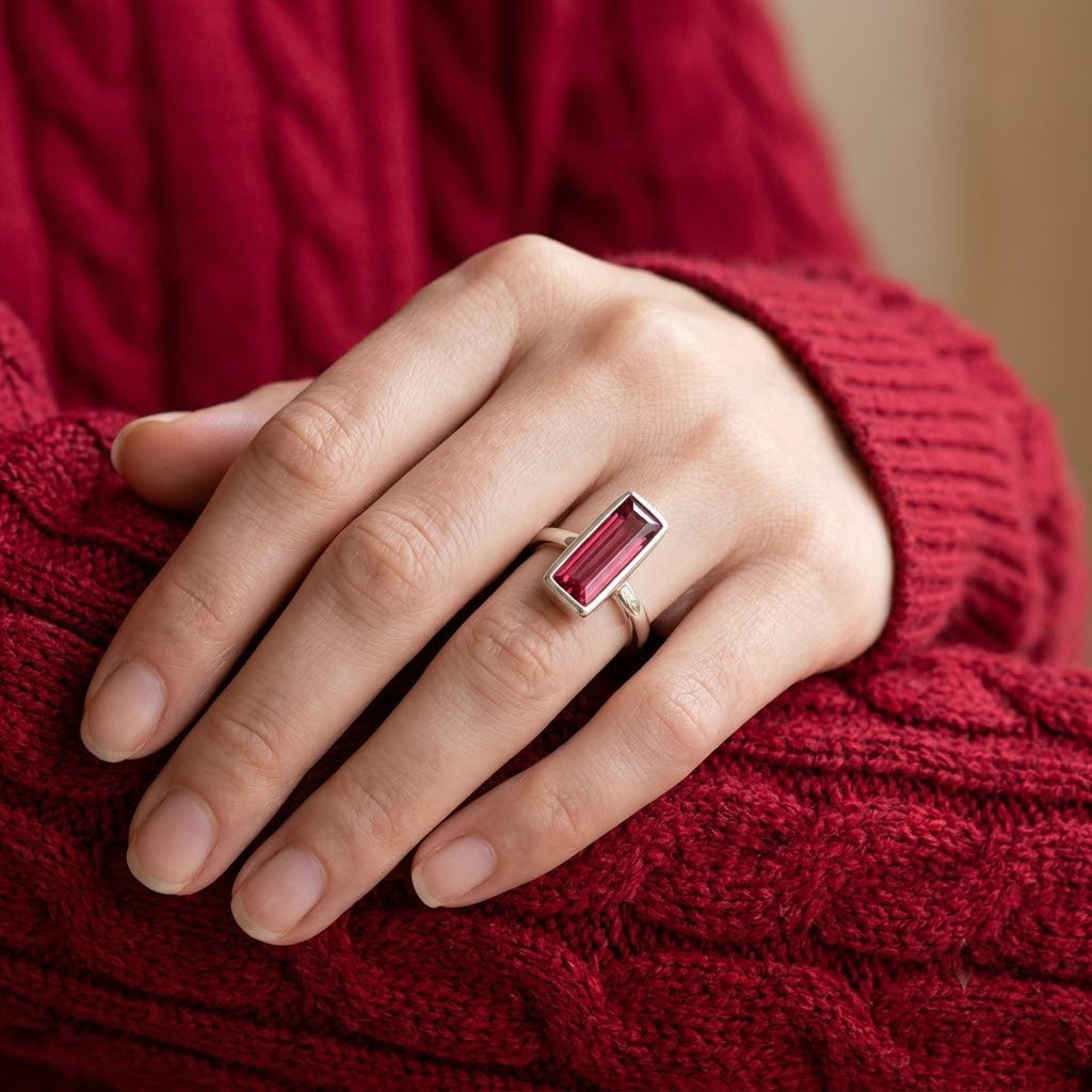 Ruby quartz Adira ring worn on a model’s hand with a burgundy sweater.