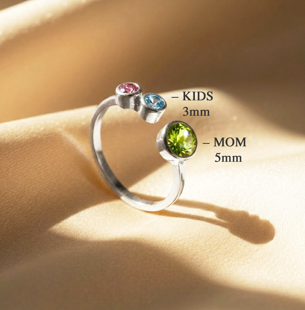 Mother’s birthstone ring showing larger center stone for mom and smaller stones for kids, personalized gold family ring with ruby, sapphire, and peridot, adjustable custom jewelry gift for mothers of multiple children.