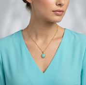 Model wearing a dainty amazonite oval bezel necklace with an aqua V-neck top.