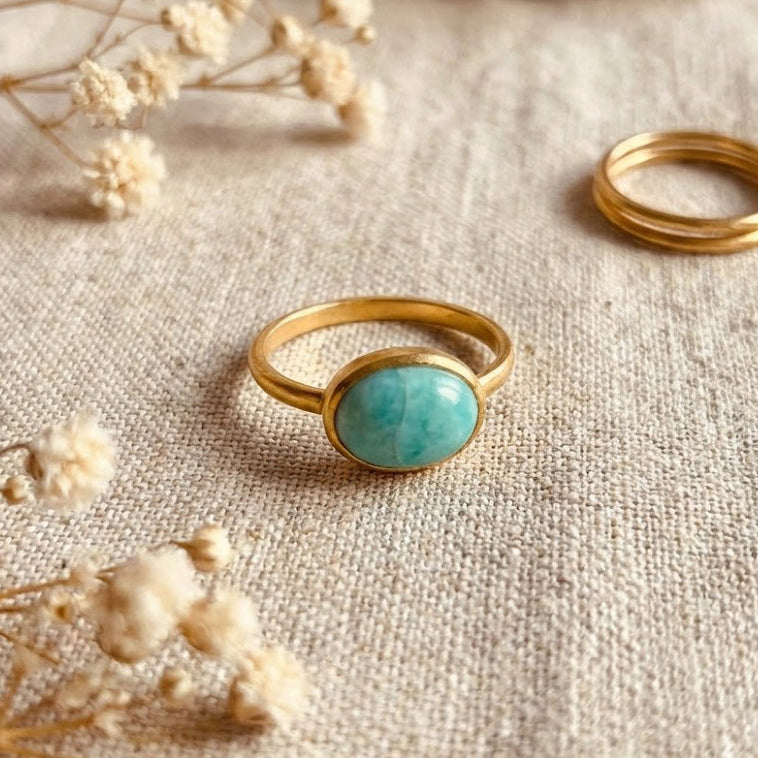 Oval amazonite ring displayed on neutral fabric with soft natural light, highlighting bezel-set turquoise gemstone and minimalist gold band. Handmade amazonite ring designed as a dainty everyday ring, modern gemstone jewelry piece, and thoughtful gift for her.