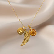 Gold angel wing memorial necklace with engraved initial disc and teardrop birthstone charm, personalized remembrance jewelry sympathy gift for loss.