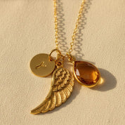 Personalized angel wing necklace featuring a natural birthstone teardrop, engraved initial disk, and gold vermeil wing charm, a meaningful memorial jewelry piece and sympathy gift for women.