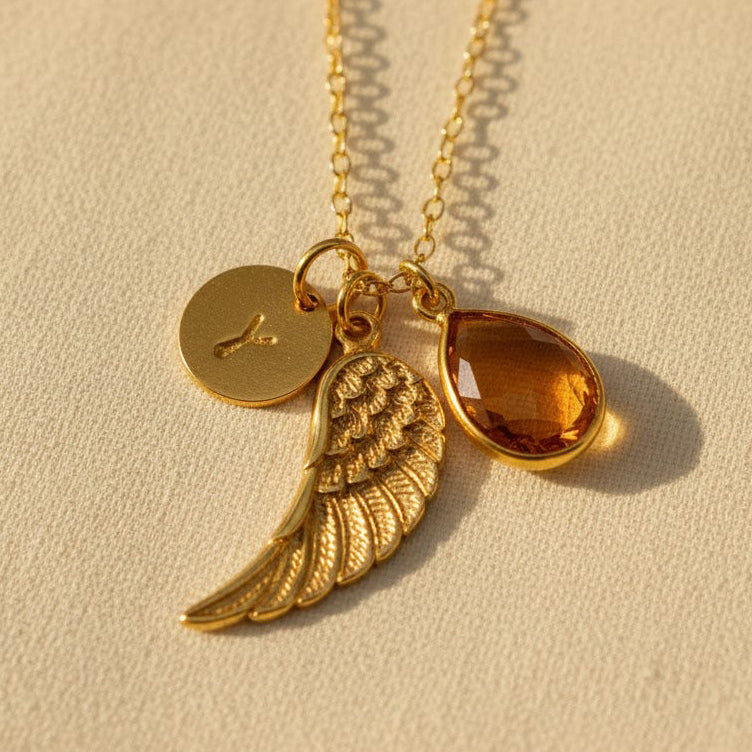 Personalized angel wing necklace featuring a natural birthstone teardrop, engraved initial disk, and gold vermeil wing charm, a meaningful memorial jewelry piece and sympathy gift for women.