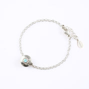 A 925 sterling silver donut bracelet with an aqua chalcedony stone and the letter "M" engraved on the bottom of the disc rests against a white background. This bracelet is hypoallergenic and is sure to make the day of anyone who receives this as a gift! This is the perfect thing for Mother's Day! 