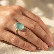 Woman wearing a large rough cut aqua chalcedony teardrop ring in sterling silver.