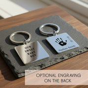 Two custom footprint keychains displayed on a neutral tray, highlighting both square and rounded rectangle shapes with engraved baby feet, name and birth date, plus note about optional engraving on the back. Personalized stainless steel keepsake for moms, dads and grandparents, unique new baby gift, first Father’s Day present or memorial keychain with baby footprints.