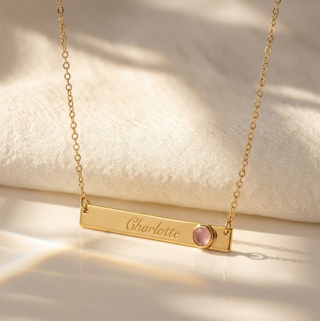 Personalized gold birthstone bar necklace engraved with name and pink gemstone
