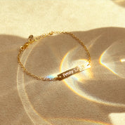 Custom engraved bar bracelet photographed in soft light, minimalist gold bar charm bracelet with personalized engraving
