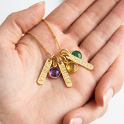 Hand holding custom engraved bar necklace with birthstones for mom, personalized children name necklace in gold