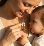Mother wearing custom engraved name necklace with birthstone charms, personalized family necklace representing children or grandchildren.