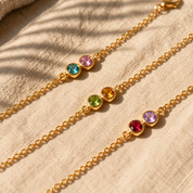 Close-up of gold rolo chain bracelets with different birthstone pairs