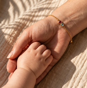 Mother wearing a two birthstone bracelet while holding a child’s hand
