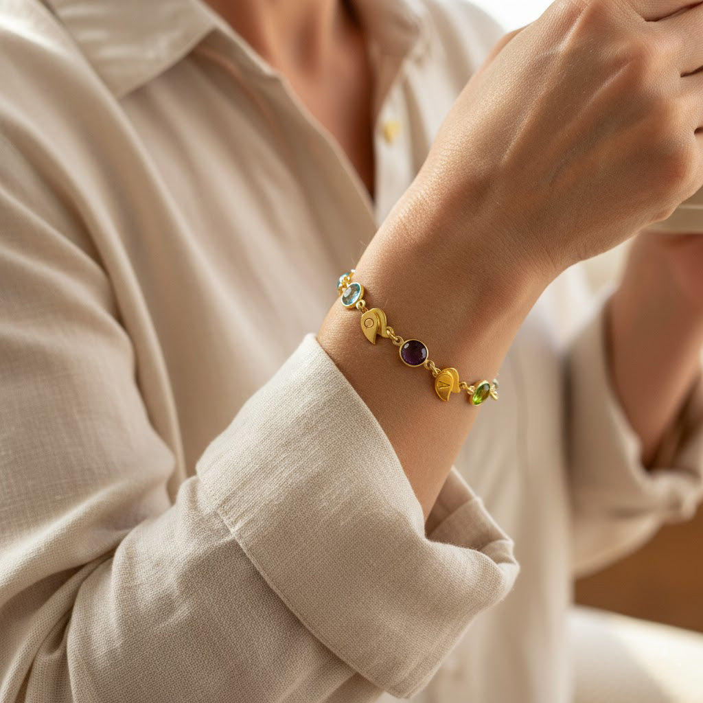 Woman wearing custom birthstone bracelet with engraved initial leaf charms, personalized mom bracelet in gold