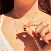 Model wearing a white lace blouse holds Dainty Large Oval Black Copper Obsidian Bezel Set Pendant on a gold filled satellite chain. Black and Gold Gemstone Jewelry Necklace, Natural Cleansing Crystal Gemstone, Clarity Gemstone, Crystal Lover