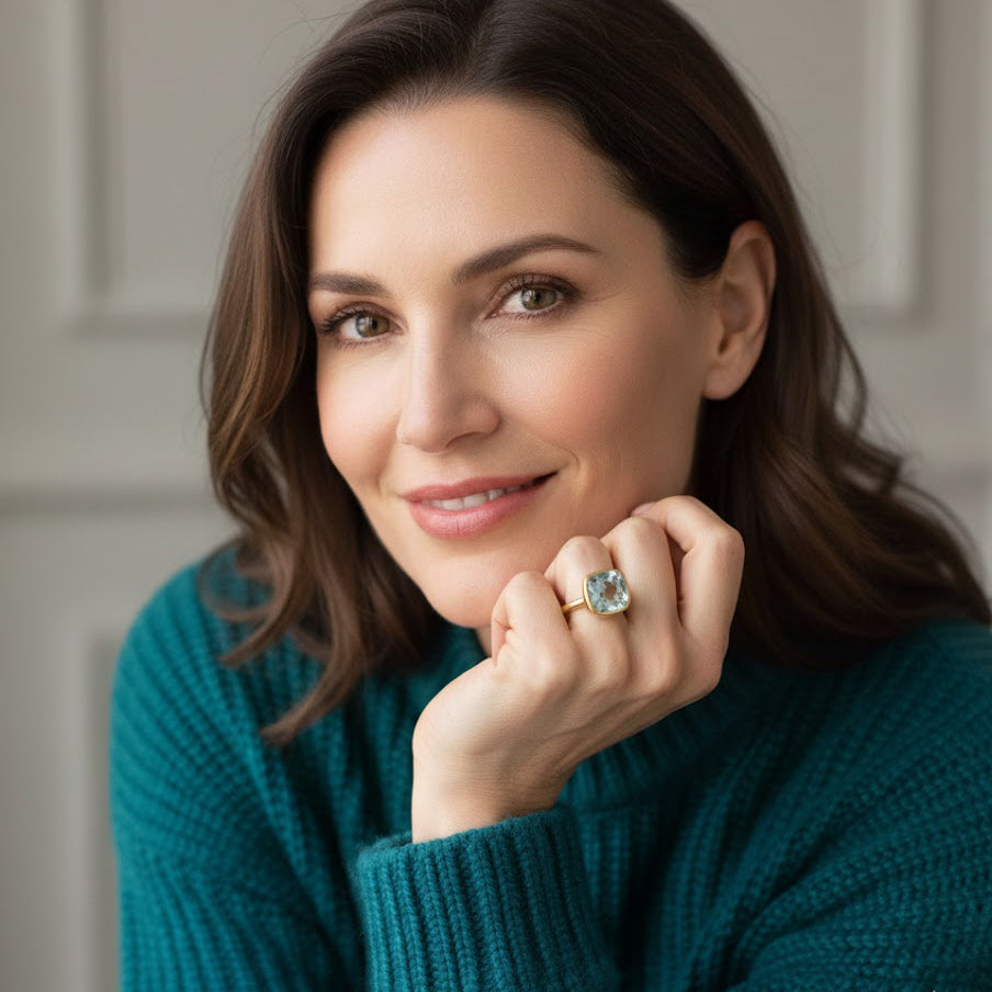 woman wearing blue topaz cushion cut gemstone ring, dainty aquamarine birthstone ring jewelry styling