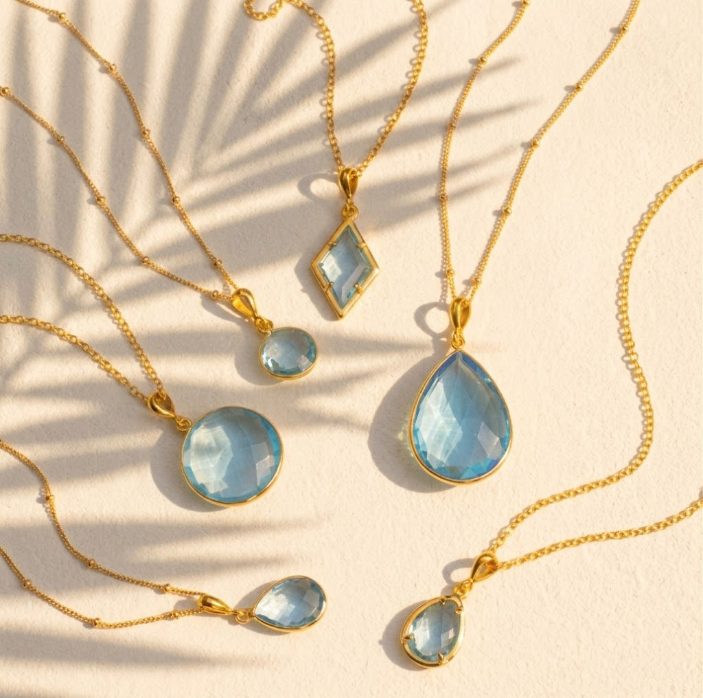 blue topaz necklace collection available in large, medium and small teardrops, prong set teardrop, prong set diamond, large and medium rounds on white background. Choose from satellite or cable chain. December birthstone. 